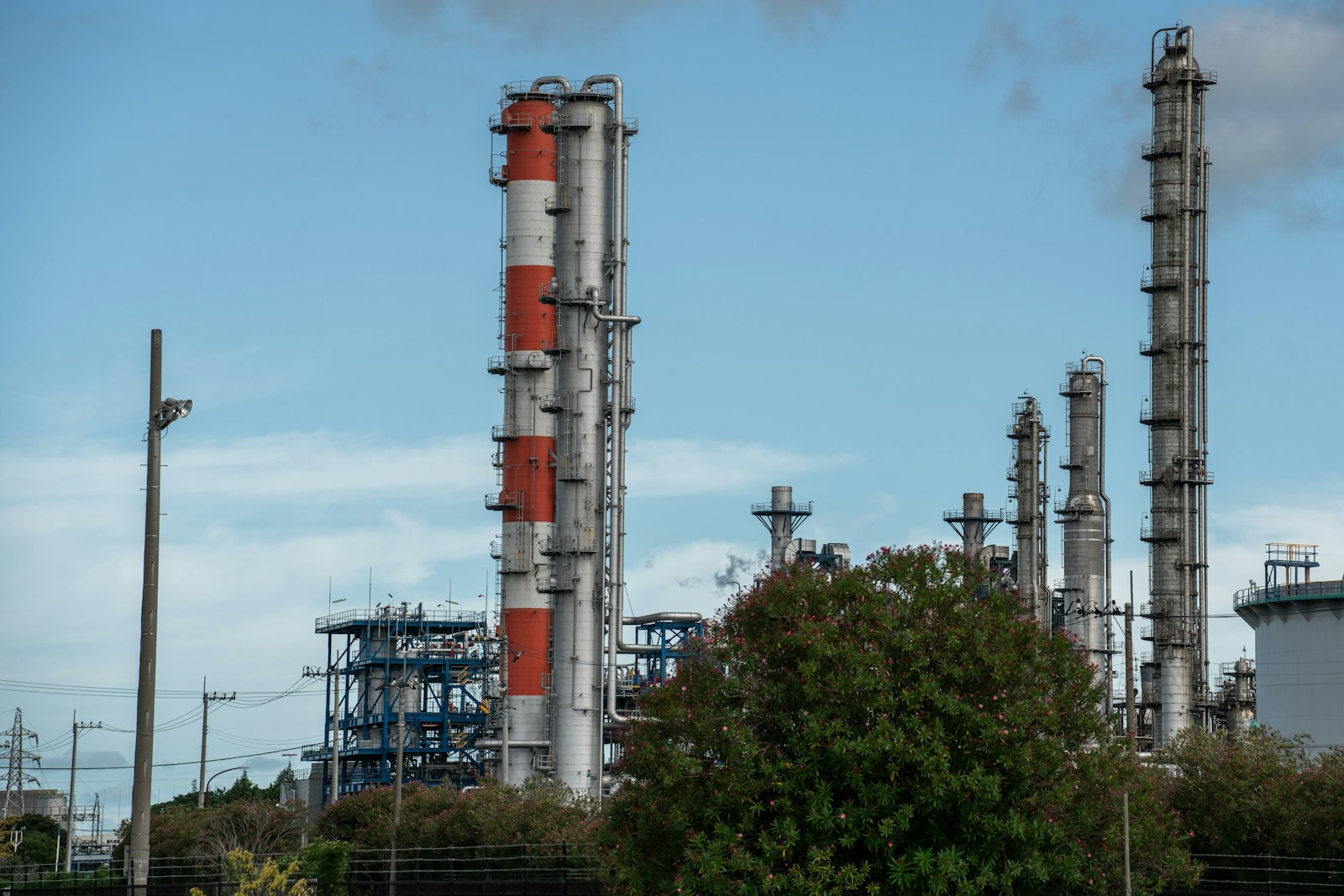 Oil refinery towers against the sky — pricing oil in dollars became the anchor of the petrodollar system